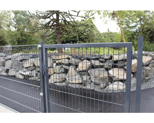 Metallzaun vor einer Steinmauer im Garten