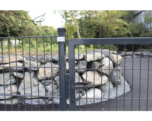 Metallzaun mit Gitter und Tor vor Steinmauer