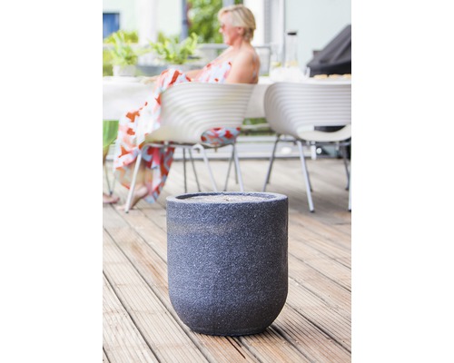 Blumentopf auf einer Holzterrasse mit Sitzbereich im Hintergrund