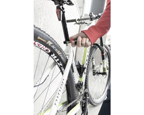 Nahaufnahme eines Fahrrads, dessen Sattelstütze mit einem Werkzeug eingestellt wird.