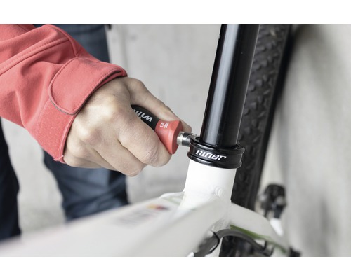 Eine Person benutzt Werkzeug am Fahrrad zur Reparatur.