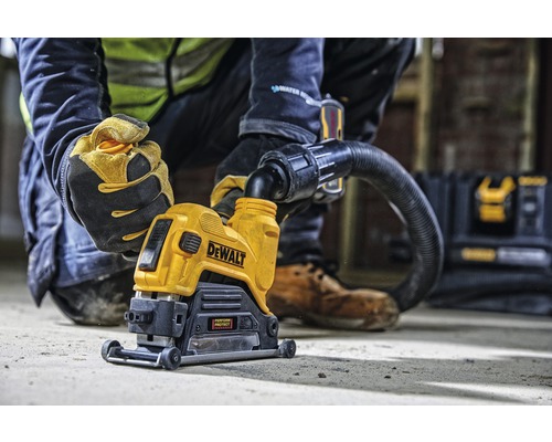 DeWalt Mauernutfräse mit einem Arbeiter, der sie bedient und einem Staubsaugeraufsatz.