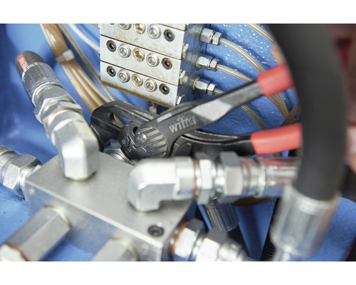 Eine Rohrzange der Marke Wiha wird an einer Hydraulikarmatur verwendet.