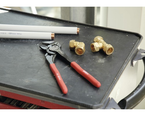 Installationszange, Rohrverbinder und Rohre auf einem Tablett