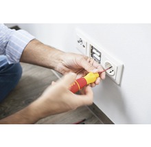 Elektriker montiert Steckdose mit Schraubendreher