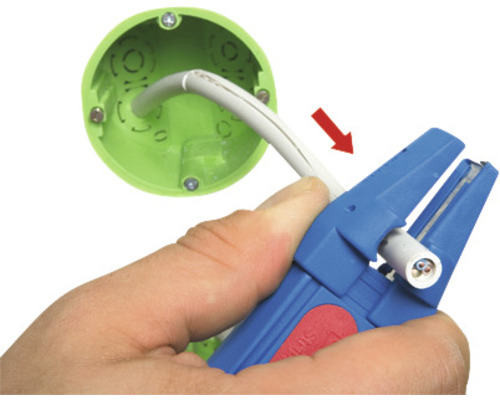 Eine Person verwendet eine Abisolierzange, um ein Kabel in der Nähe einer Wandsteckdose abzuisolieren.