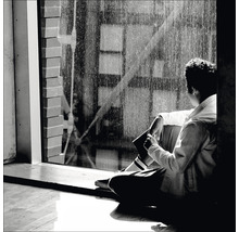 Eine Person sitzt am Fenster und schaut nach draußen.