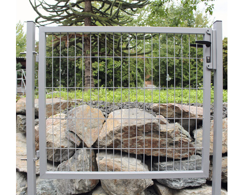 Gartenzaun mit Metallgitter und Tor vor einer Steinmauer