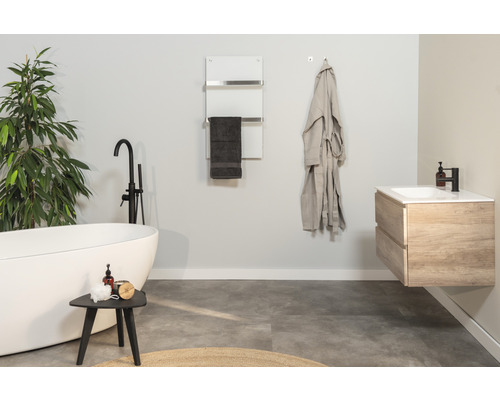 Badezimmer mit freistehender Badewanne, Waschtisch, Handtuchwärmer und Dekorationen für eine helle und moderne Atmosphäre