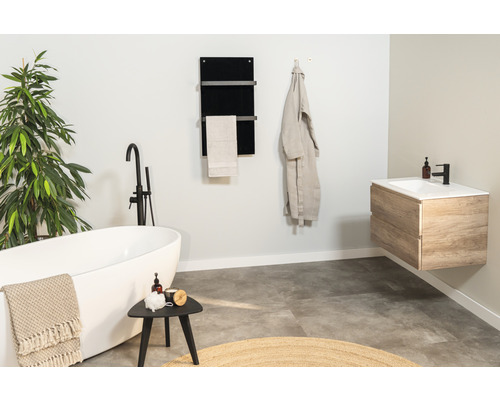 Helles Badezimmer mit Badewanne, Waschtisch, Handtuchwärmer und Pflanze für eine angenehme Atmosphäre.