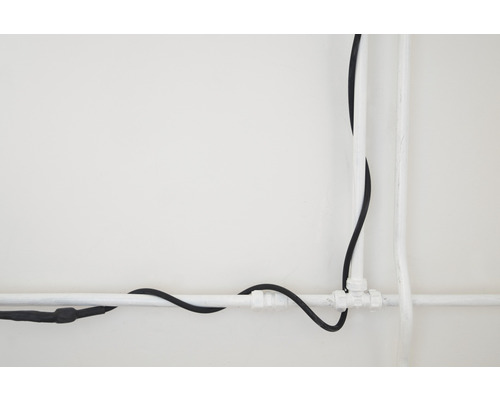 Installation mit Kunststoffrohren und einem Elektrokabel an einer Wand