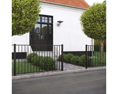 Vorgartenzaun PLUS Basic 150 x 85 cm RAL 9005 schwarz Schwarzer Metallzaun vor einem Haus mit Bäumen und gepflastertem Weg