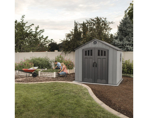 Gartenszene mit Gerätehaus und zwei Personen bei der Gartenarbeit