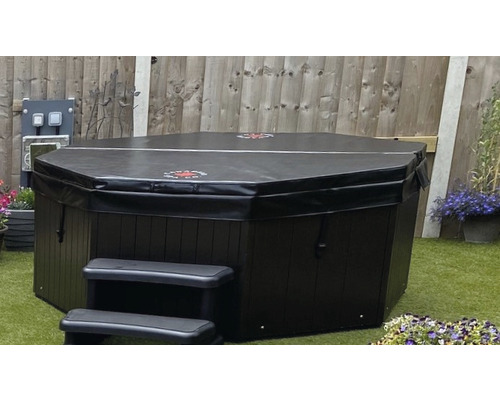 Abgedeckter, dunkler Whirlpool mit Treppe im Garten