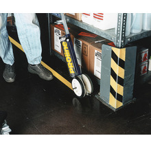 Person zieht mit einem Markierungswagen eine Linie auf dem Boden.