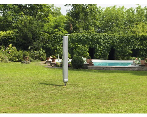 Geschlossener Gartenschirm mit Schutzhülle auf einer Rasenfläche in einem Garten mit Pool