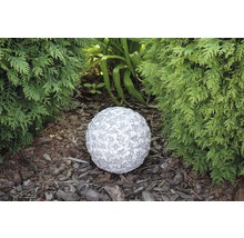 Dekorative Gartenkugel mit Blumenmuster zwischen Pflanzen