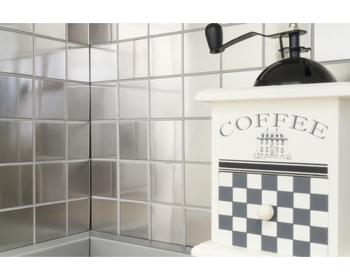 Quadratische Metallfliesen an der Wand mit einer dekorativen Kaffeemühle
