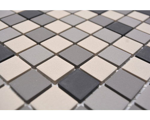 Mosaikfliesen mit quadratischen Elementen in verschiedenen Grautönen.