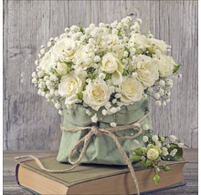 Strauß mit weißen Rosen und Schleierkraut in grüner Papiertüte auf einem Buch