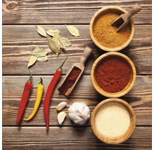 Anordnung von Gewürzen, Knoblauch, Chili und Lorbeerblättern auf einer Holzoberfläche