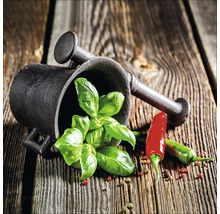 Mörser mit Stößel, Basilikum und Chili auf einem Holztisch