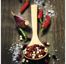 Holzlöffel gefüllt mit Pfefferkörnern, Knoblauchzehe und Chilischoten auf einem Tisch.
