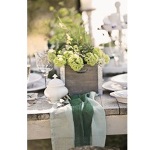 Tischdekoration mit Blumenarrangements in Holzkiste, Porzellanzuckerdose und Stoffserviette