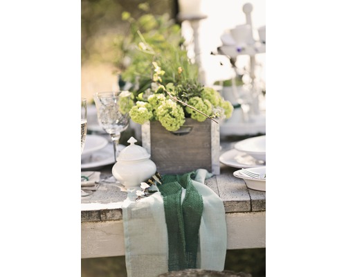 Tischdekoration mit Blumenarrangements in Holzkiste, Porzellanzuckerdose und Stoffserviette