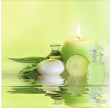 Stillleben mit Kerzen, Aromaölflaschen, Limettenscheibe und Blättern im Wasser