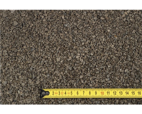 Nahaufnahme von Basalt Splitt mit einem gelben Maßband zur Größenreferenz