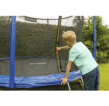 Ein Junge an einem Trampolin mit Sicherheitsnetz im Garten.