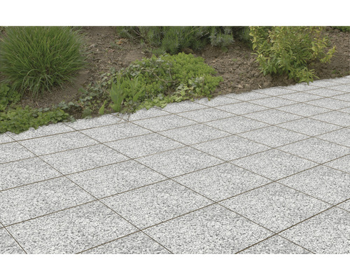 Quadratische Terrassenplatten aus Stein im Außenbereich neben einer Pflanzfläche