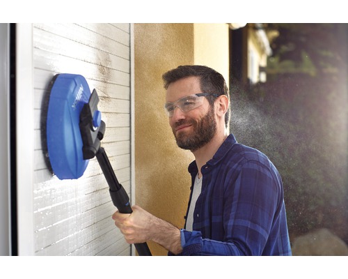 Mann reinigt Wand mit rotierender Bürste und Hochdruckreiniger