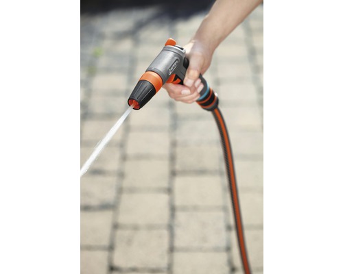 Eine Hand hält eine Gartenspritze mit Wasserstrahl.