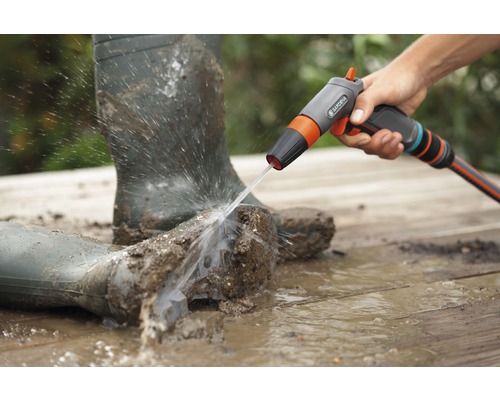 Schmutzige Gummistiefel werden mit einem Gardena Reinigungssprühgerät gereinigt