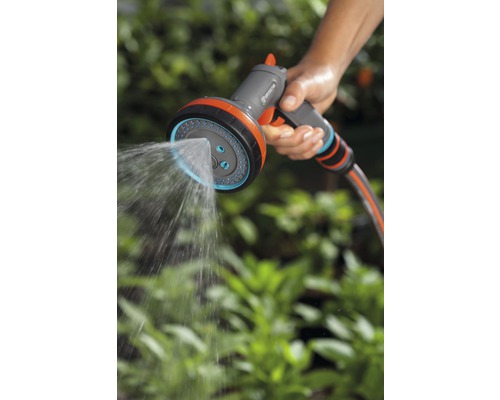 Eine Person hält eine Gardena Mehrzweck-Gartenspritze, die Wasser versprüht.