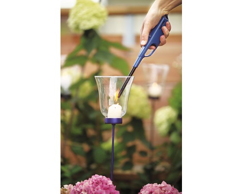 Eine Hand zündet eine Kerze in einem Windlicht mit einem Stabfeuerzeug an.