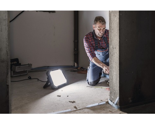 Handwerker bei der Arbeit mit Baustrahler zur Ausleuchtung
