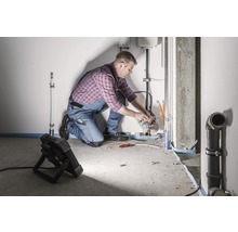 Ein Installateur arbeitet an Rohrleitungen in einem Raum.