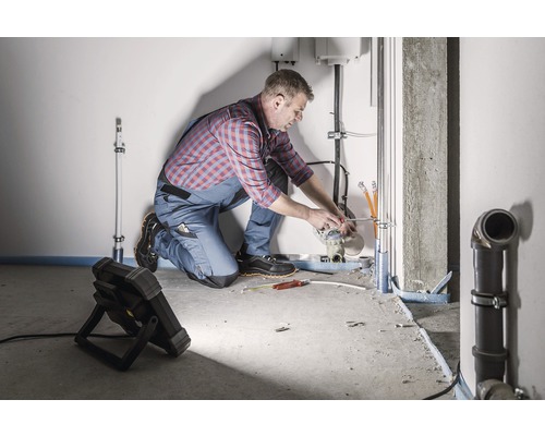 Ein Installateur arbeitet an Rohrleitungen in einem Raum.