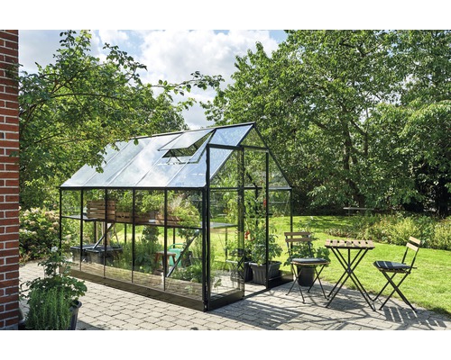 Gewächshaus im Garten mit Pflanzen und Gartentischgruppe