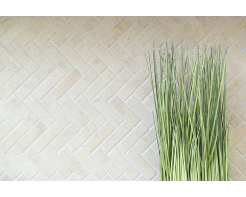 Helle Wandfliesen im Fischgrätmuster mit dekorativem Ziergras