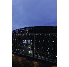 Balkon mit Lichterkette und Blick auf eine abendliche Stadt.