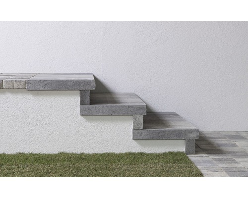 Außentreppe aus Beton mit drei Stufen vor einer Wand und Gras