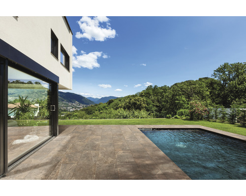 Terrasse mit Steinplatten neben einem Schwimmbecken und einem Haus