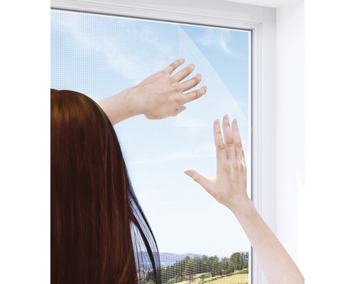 Person bringt ein Fliegengitter an einem Fenster an