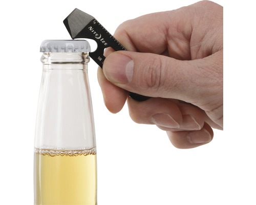 Eine Hand benutzt einen schwarzen Mehrzweckschlüssel von Nite Ize, um eine Glasflasche mit gelbem Inhalt zu öffnen