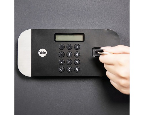 Yale Logo. Detailansicht eines Tresors mit digitalem Tastenfeld und einer Hand, die einen Schlüssel einführt.