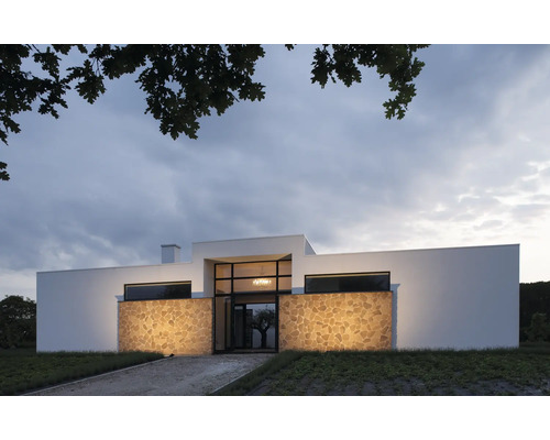 Modernes Haus mit Natursteinfassade und großen Fensterflächen.